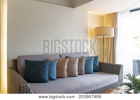 Wicker furniture and colorful cushions. Decoration of living room in colorful theme.
