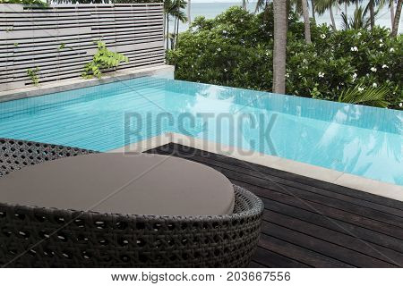 Wicker furniture edge the terrace pool for relaxation.
