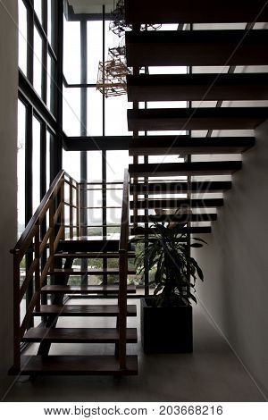 Silhouette of wooden staircase. Hight glass window.