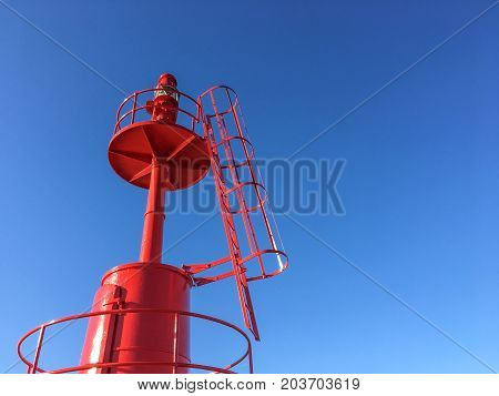 Red Lighthouse at port with blue sky .