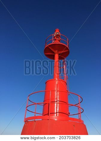 Red Lighthouse at port with blue sky .