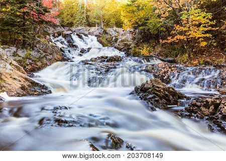 Waterfall on a creek through the wood in Canada long exposure imahe with smooth water effect. Nature and relax concepts