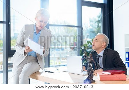 mature business colleagues discussing documents in office