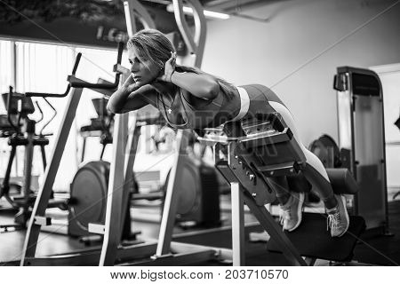Athletic young woman doing hyperextension in the gym. Woman flexing back and abdominal muscles on bench