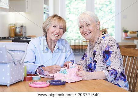 Portrait Of Two Senior Women Sewing Quilt Together