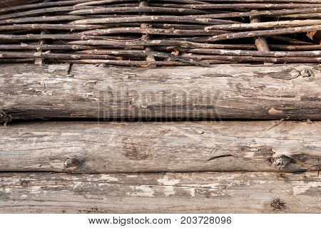 Old wooden wall with logs and wicked twigs
