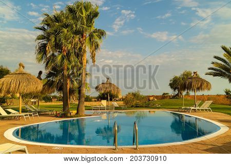 CAMPOS MALLORCA SPAIN - August 30 2017: Panorama of a swimming pool from a Mediterranean finca buildings built in traditional island style and garden with palm trees and orange trees. Balearic islands. Summer 2017.