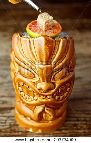 Cocktail zombie in a glass of tiki exotic cocktail with fire on a bar counter on a blurred background