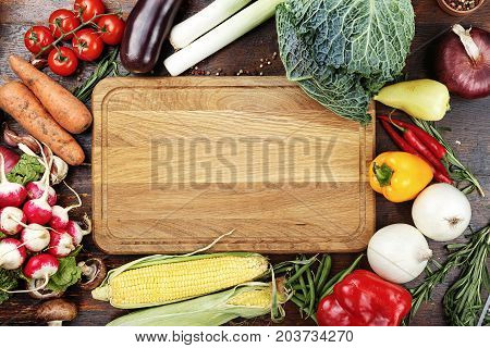 herbs and spices vegetables and sauces on wooden background in the middle of table is cutting bord like a space for text