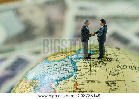 Miniature figure men handshaking standing on north korea and japan map globe as peace and war agreement nagotiation concept.