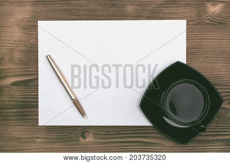 Empty Letter page fountain pen and cup of coffee on the burnt table background. Writter desk table.