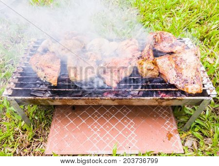 Pork shoulder grilled on the small metal stove for babecue party beside the house.