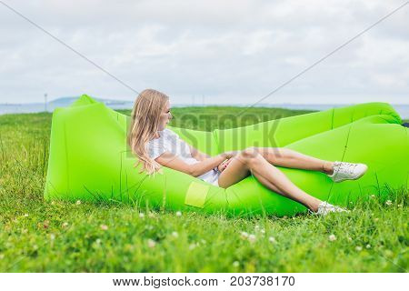 Young woman resting on an air sofa in the park.. lamzac