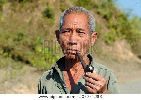 BAGAN MYANMAR - 24 JANUARY 2011: Portrait of the Burmese smoking a pipe