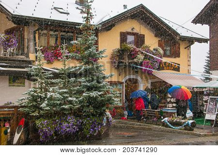 LIVIGNO, ITALY - SEPTEMBER 10, 2017: Tourists shopping on the streets of duty-free area in Livigno during snowy day