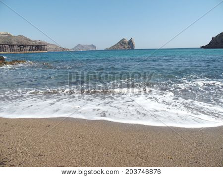 playa con oleaje e isla al fondo