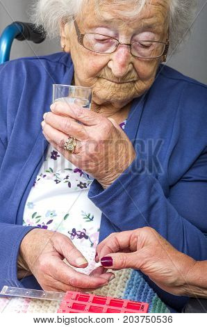 Senior Citizen taking Pill.
A senior citizen, in a wheelchair, being given her medication by a carer.