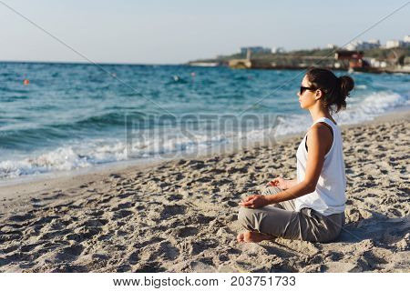 Young woman practicing yoga on the beach.
