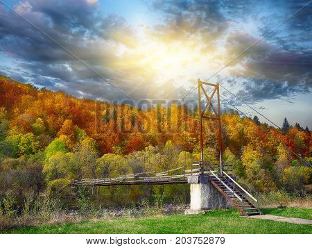 Wooden bridge over mountain river. Dramatic dark sky. Autumn time