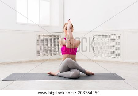 Fitness, woman training yoga in eagle pose at home. Young slim girl makes exercise.
