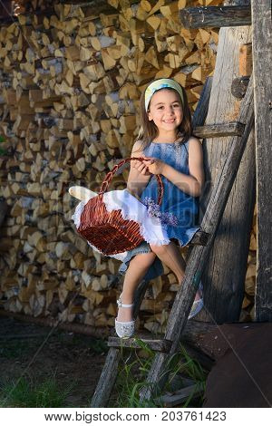 child smiling with no teeth sitting near the wooden wall of the shed.