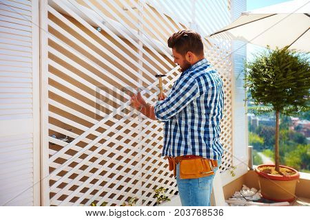 Young Adult Man Decorating The House Wall, By Setting Up The Wooden Trellis For Climbing Plants