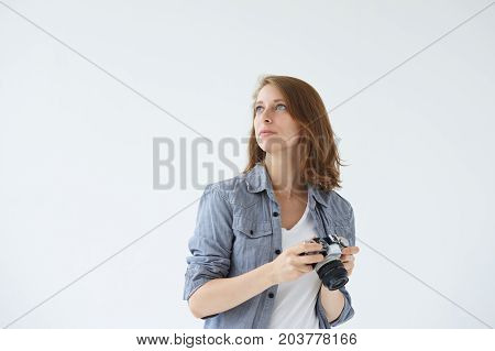 Waist up shot of self-employed female stock photographer working in studio holding digital camera in her hands searching for best perspective and angle. People hobby profession and occupation