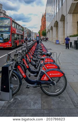 London UK - May 31 2017 Row of Santander Cycles ready for hire in High Holborn. with bus and cab passing on the road.
