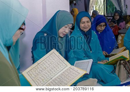 Labuan,Malaysia-Aug 30,2017:Muslim woman perform Quran recitation during Aqiqah ceremony in Labuan,Malaysia.Islamic traditions after a baby is born include shaving his head & sacrificing an animal.
