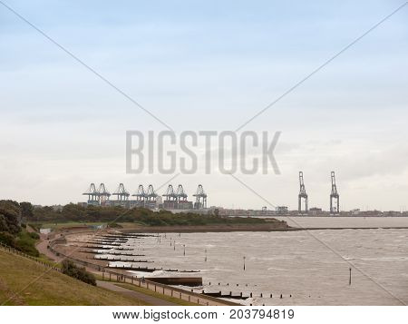 Sea Industry Cargo And Shipping Cranes In The Distance Beach Groynes Harwich Port