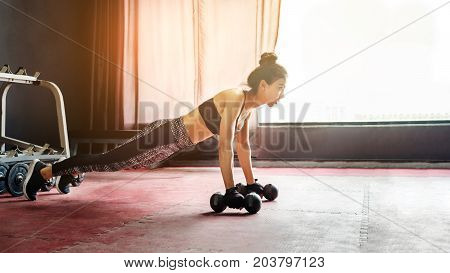 Asian Sports Woman Doing Exercises With Dumbbell And Push-ups At The Gym