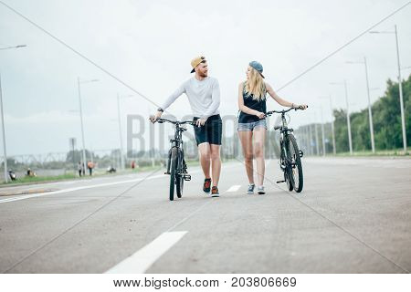Man And Woman Walk Their Bikes Down The Road
