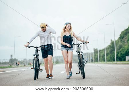 Young Couple Walking Bikes Together On The Road