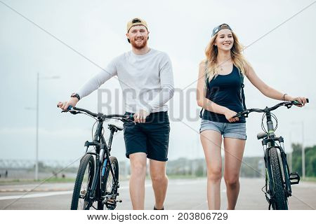 Young Couple Walking Bikes Together On The Road