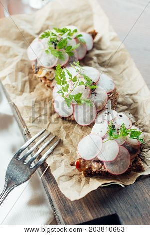 Slices Of Radish On Cereal Bread With Board