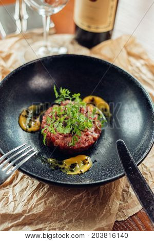 Beef Tartar With An Egg On A Stone Plate. Cherry Tomatoes. Rosemary. Spice.