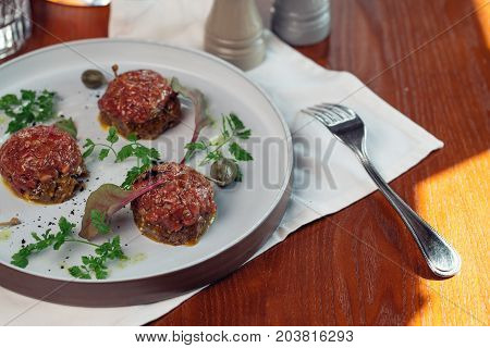 Beef Tartar With An Egg On A Stone Plate. Cherry Tomatoes. Rosemary. Spice.