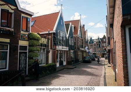 Volendam Netherlands - 26 April 2017: Resident of the village of Volendam by bike in front of the typical traditional houses of a Dutch fishing village Netherlands.