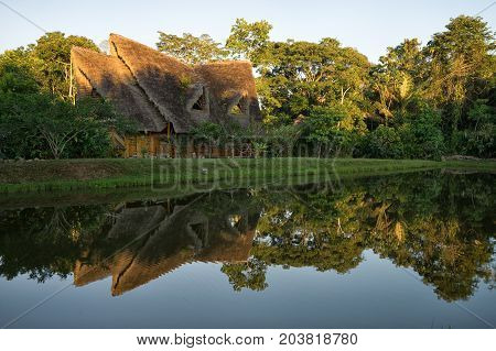 June 6 2017 Puerto Misahualli: eco lodge built from bamboo in the jungereflecting nto water at sunset