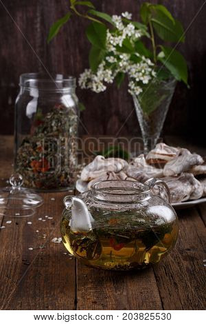 Herbal tea in glass teapot on wooden background. Rustic style.