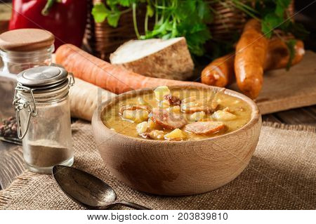 Wooden Bowl Of Split Pea Soup With Sausage And Potatoes