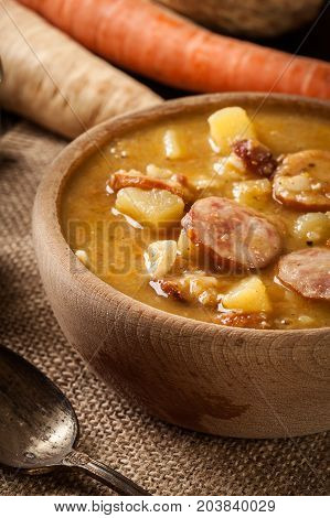 Wooden Bowl Of Split Pea Soup With Sausage And Potatoes