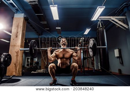 Muscular strong fitness man doing deadlift of a barbell in modern fitness center. Functional training. Snatch exercise. Scream for motivation