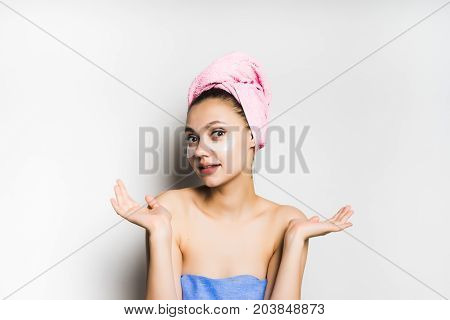 A young girl after bathing with a towel on her head is surprised, looking into the camera. Isolated on white background