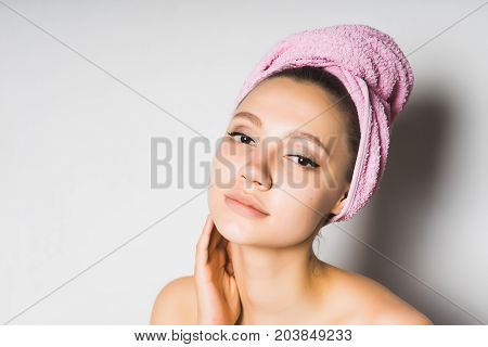 Young girl after bathing with a towel on her head tiredly looks at the camera, smiling