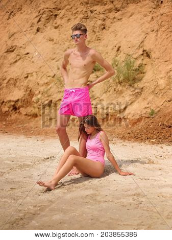 Couple in pink swimsuites. Full length photo of travel vacation and lifestyle concept. Enjoying beautiful sunset on the beach together. Honeymoon vacation. Natural and sea view on the background.
