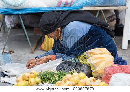 MAy 20 2017 Otavalo Ecuador; indigenous kechwa woman cleaning beans in the market on the ground