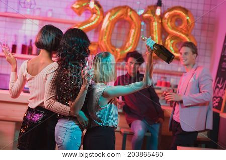 back view of women hugging each other while celebrating new year with friends