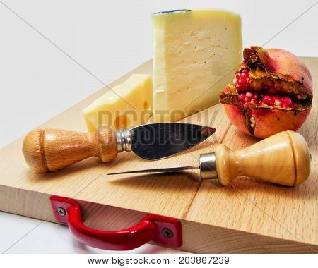 wood chopping board with assortment of cheeses and pomegranate fruit. for food concept