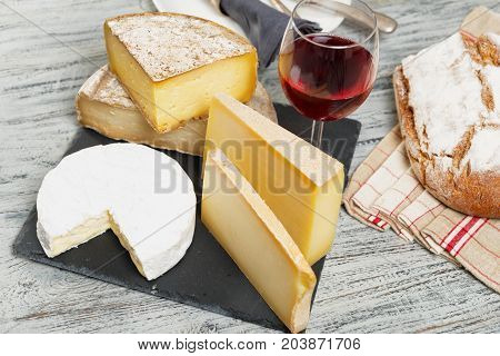Different french cheeses with a glass of red wine